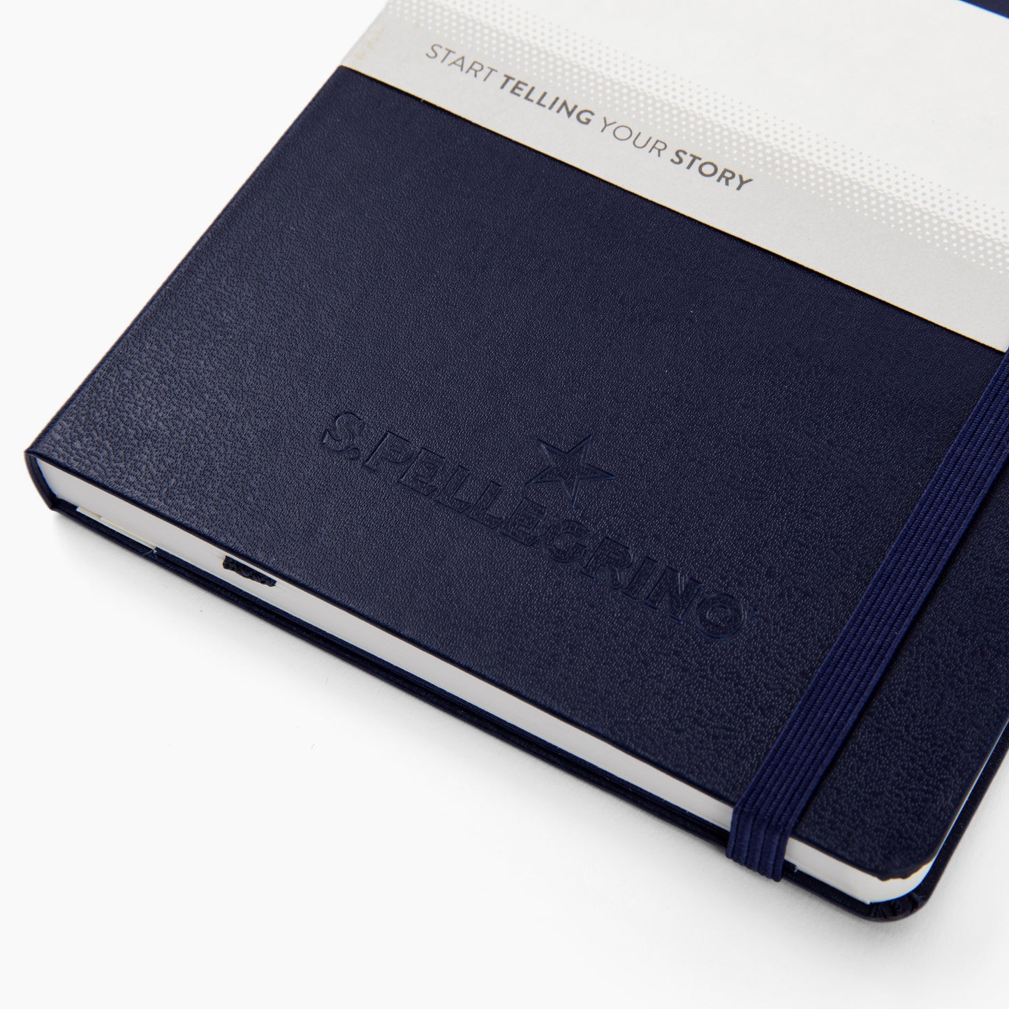 Navy blue notebook with embossed S. Pellegrino logo and elastic band, labeled “Start Telling Your Story.”